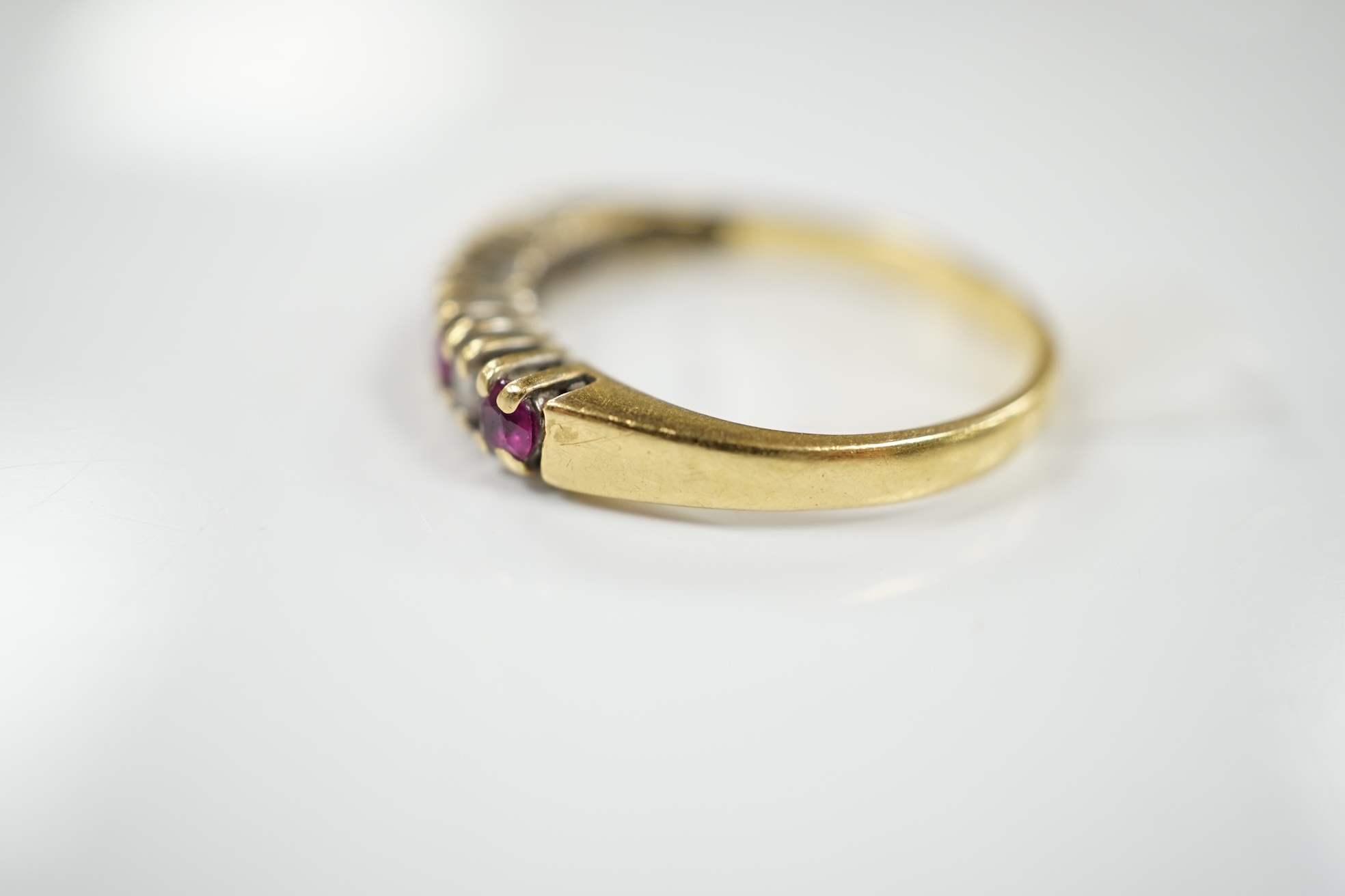 A modern 18ct gold, four stone ruby and three stone diamond set half hoop ring, size P, gross weight 2.8 grams. Condition - fair